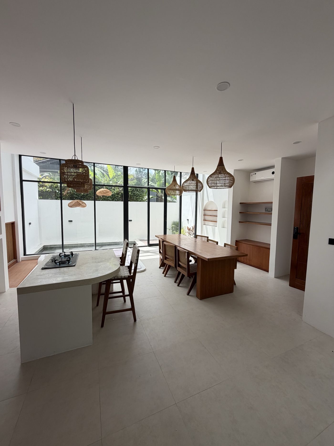 On site, Villa 1: kitchen island in cast stone with timber joinery, open to the dining volume
