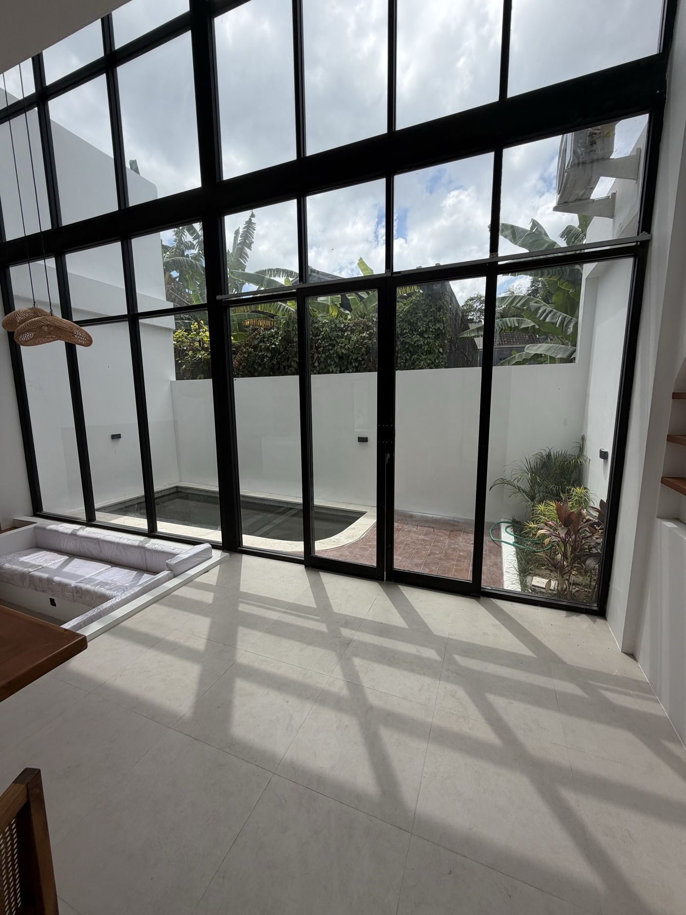 On site, Villa 1: double-height living volume, afternoon light through the black-steel glazing wall