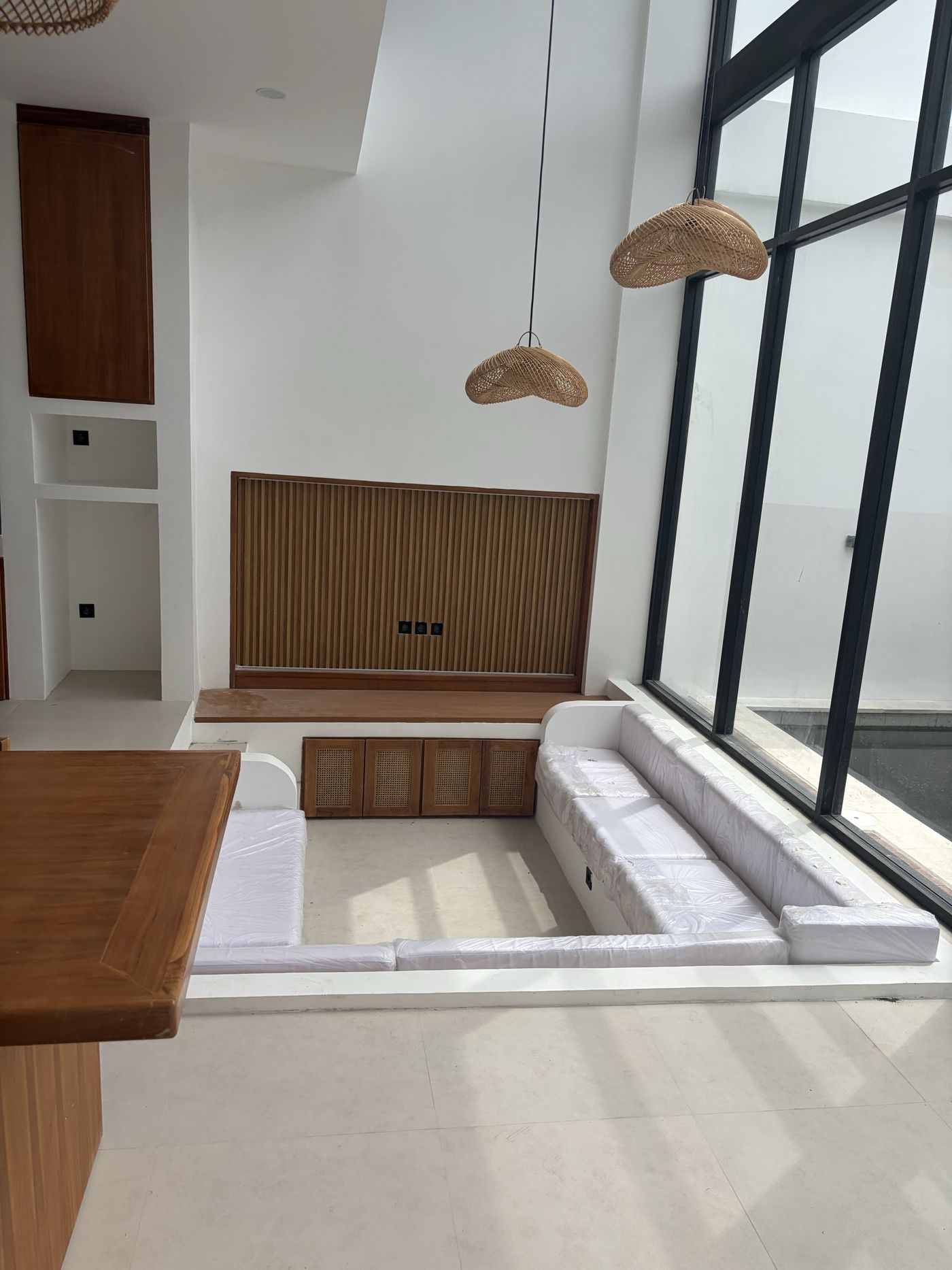 On site, Villa 1: sunken lounge below the mezzanine, slatted timber panel and woven pendants