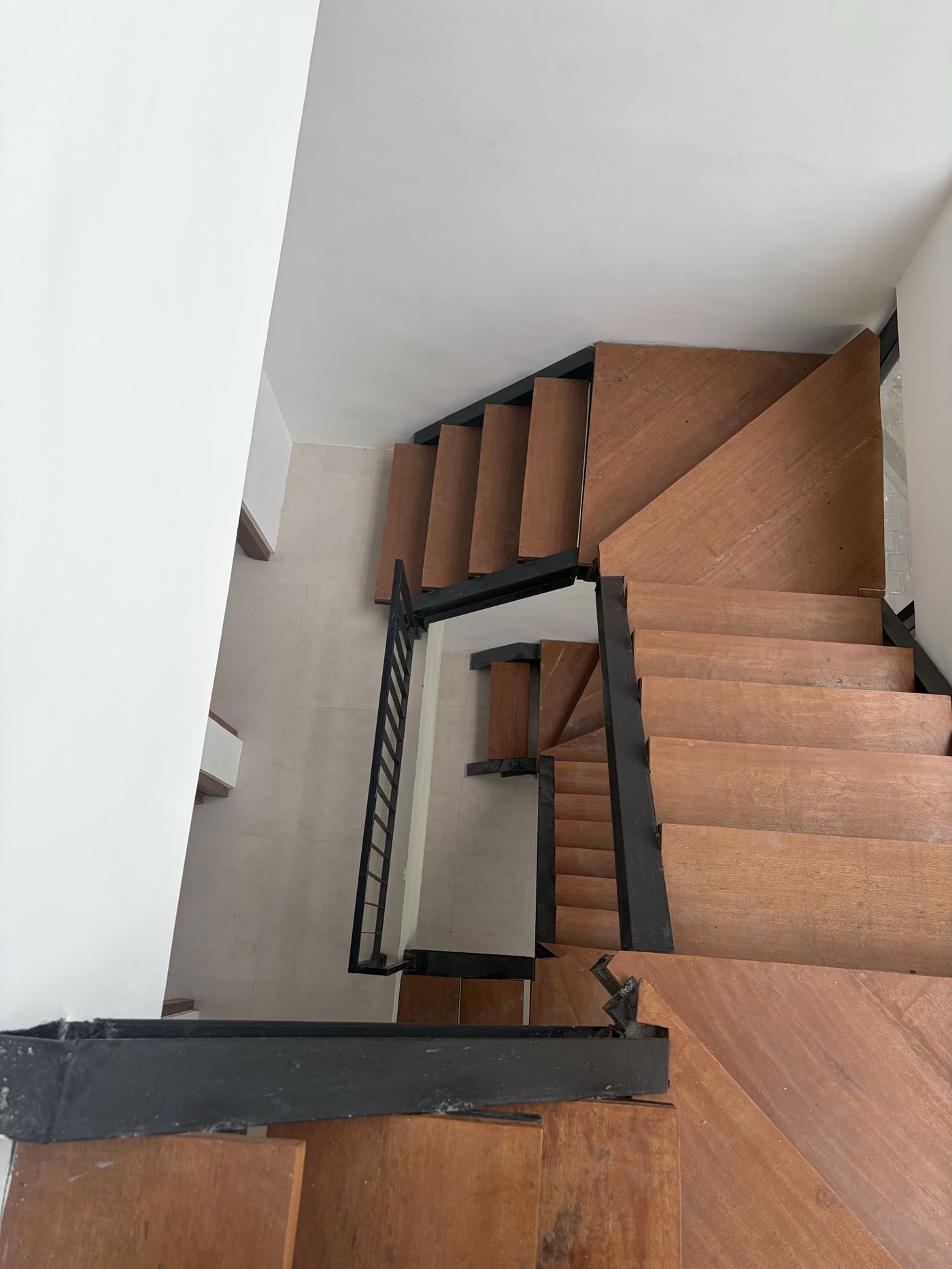 On site, Villa 1: solid timber treads on the black-steel stair, seen from the mezzanine