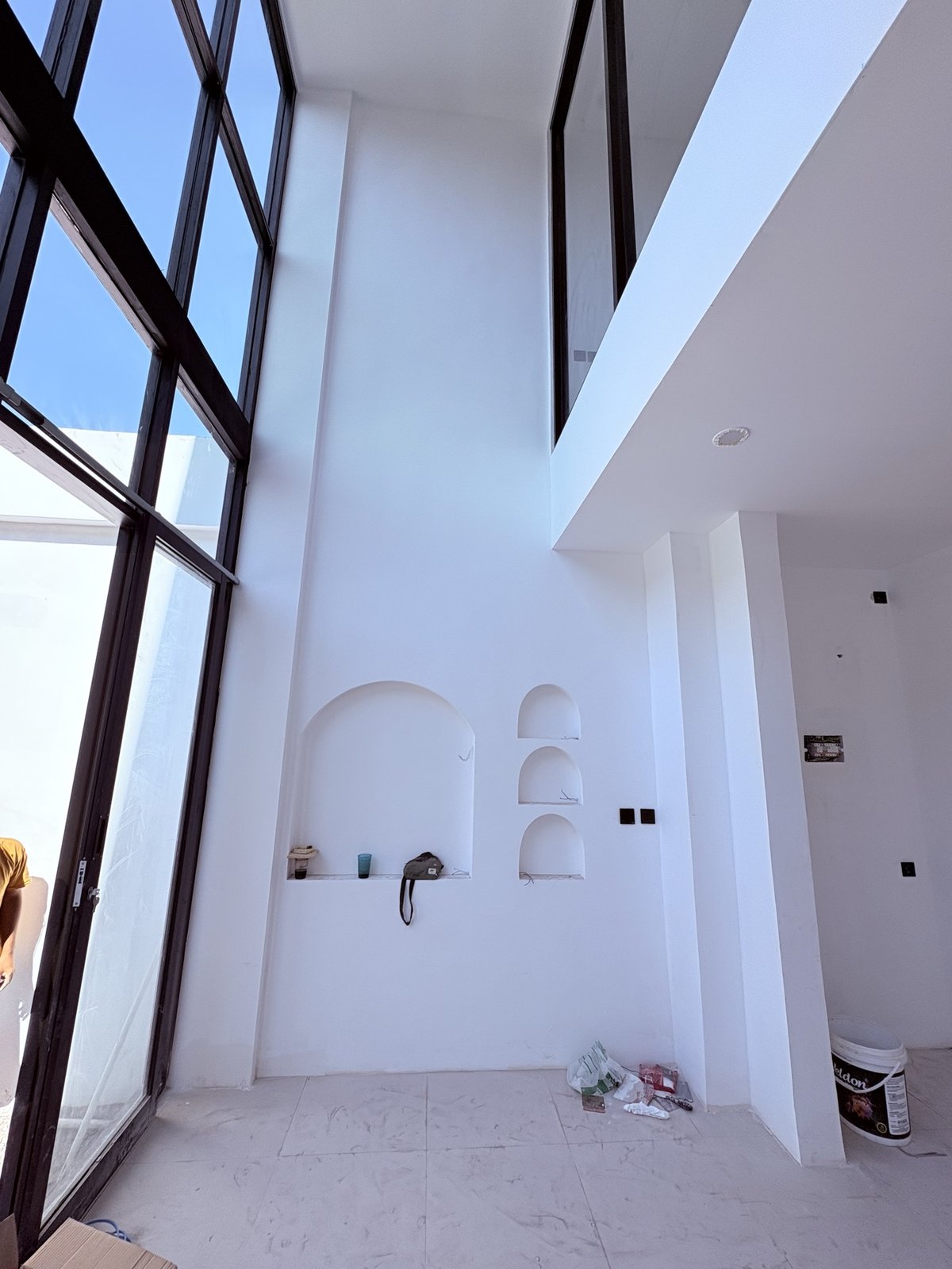 On site: double-height wall with arched display niches beside black-framed glazing