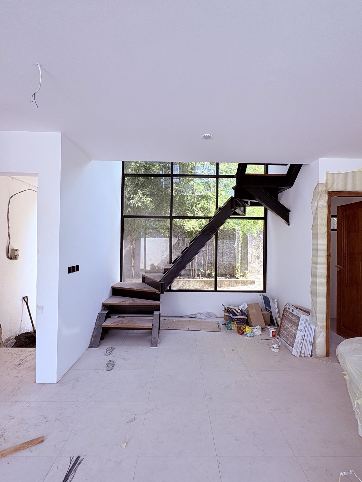 On site: black-steel floating staircase rising against full-height glazing onto the garden